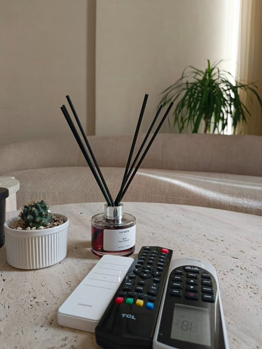 HE NOTE reed diffuser placed elegantly on a wooden coffee table next to flowers and books