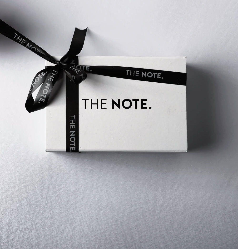 THE NOTE premium fragrance gift set in a sleek white box, elegantly wrapped with branded black ribbon, ideal for luxury gifting.